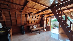 A spacious room with a wooden ceiling, a sofa, a coffee table, and a staircase leading outside. - D'Cabin Villa Uluwatu (Pecatu)