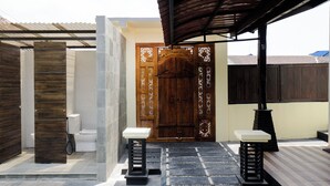 Un espacio al aire libre techado con una puerta de madera, un inodoro y dos mesas.