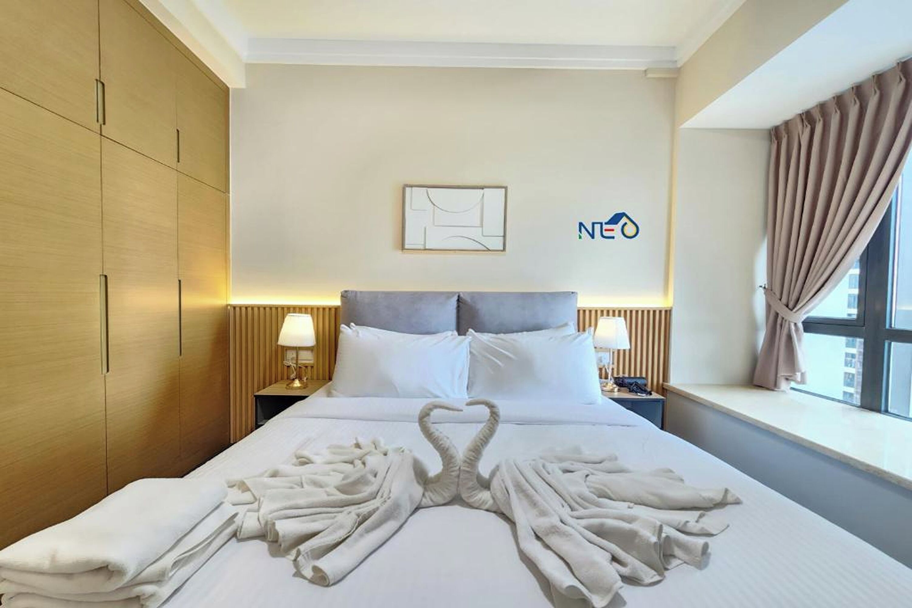 Habitación de hotel con cama, dos mesitas de noche, un cuadro en la pared y una ventana con cortinas.
