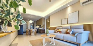 A modern living room with a sofa, a dining area, and a kitchen in the background. - R&F Princess Cove Designer Suites By Neo (Johor Bahru)