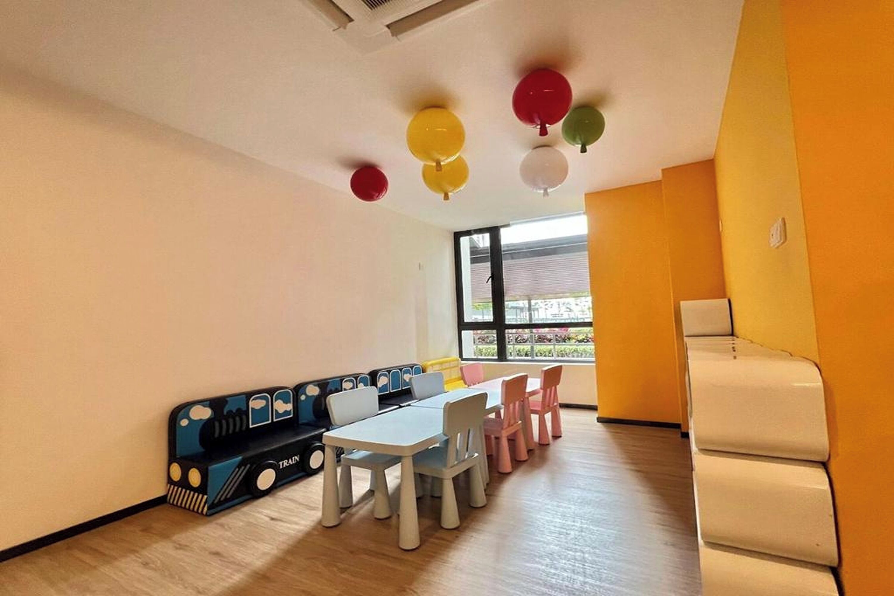 A children's play area with a train-themed seating arrangement, a table, and chairs.