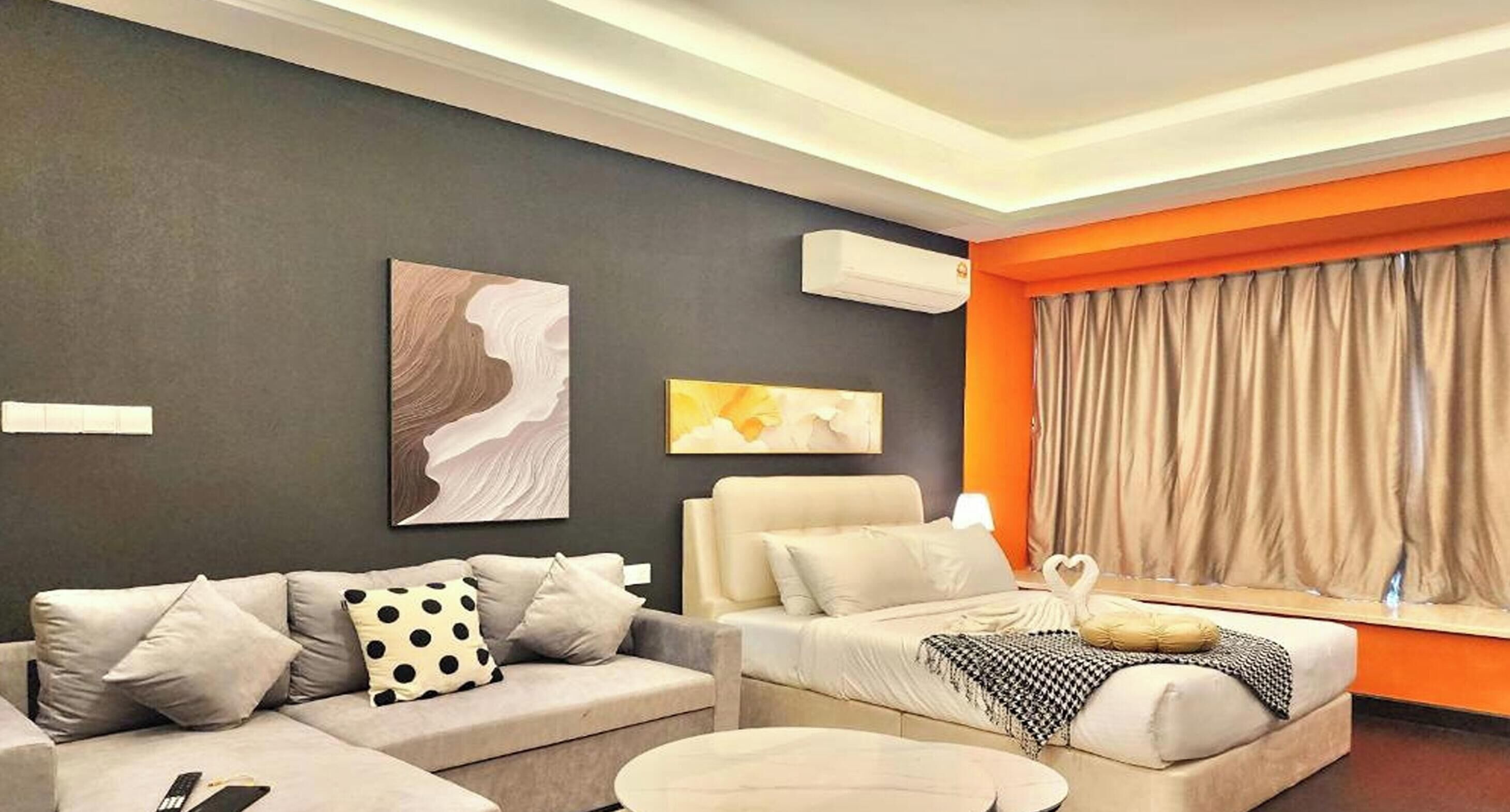 A modern hotel room with a sofa, a bed, a coffee table, and artwork on the walls.