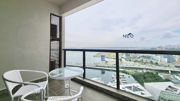 A balcony with a view of a river and cityscape, a white wicker chair, and a small round table. - R&F Princess Cove Designer Suites By Neo (Johor Bahru)