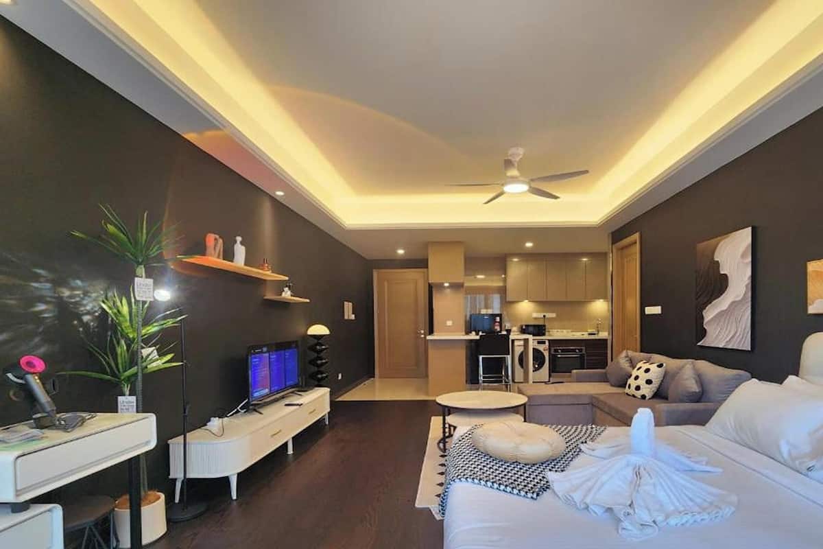 A modern living room with a sofa, TV, and a dining area.