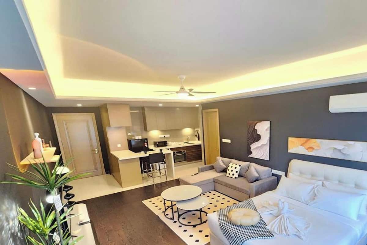 A modern hotel room with a bed, a desk, a chair, and a dining area.