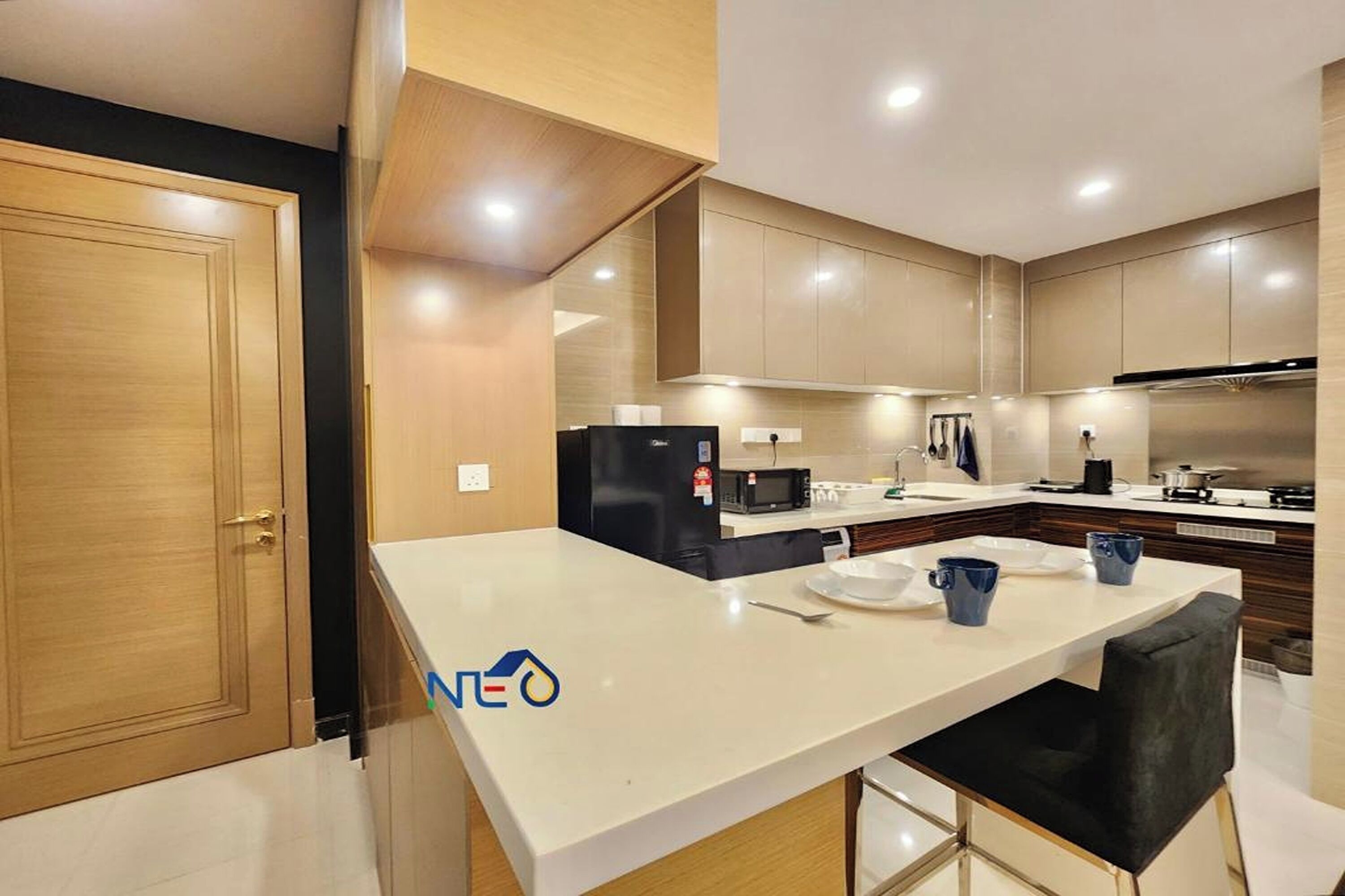 A modern kitchen with a central island, built-in appliances, and a dining area with bar stools.