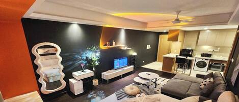 Ein modernes Wohnzimmer mit einer Couch, Fernseher und einem außergewöhnlichen Wanddesign.
