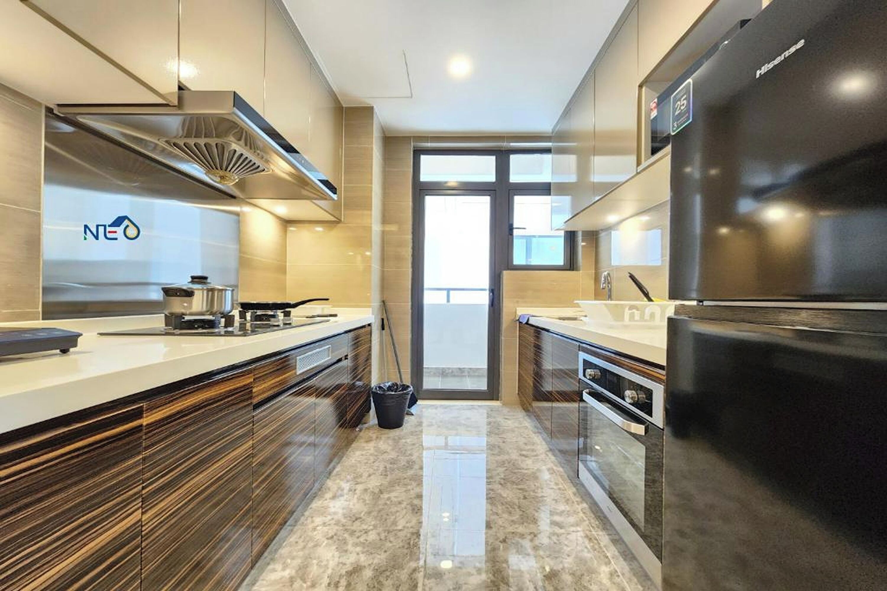 A modern kitchen with a built-in oven, a black refrigerator, and a window providing natural light.