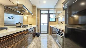 A modern kitchen with a built-in oven, a black refrigerator, and a window providing natural light.