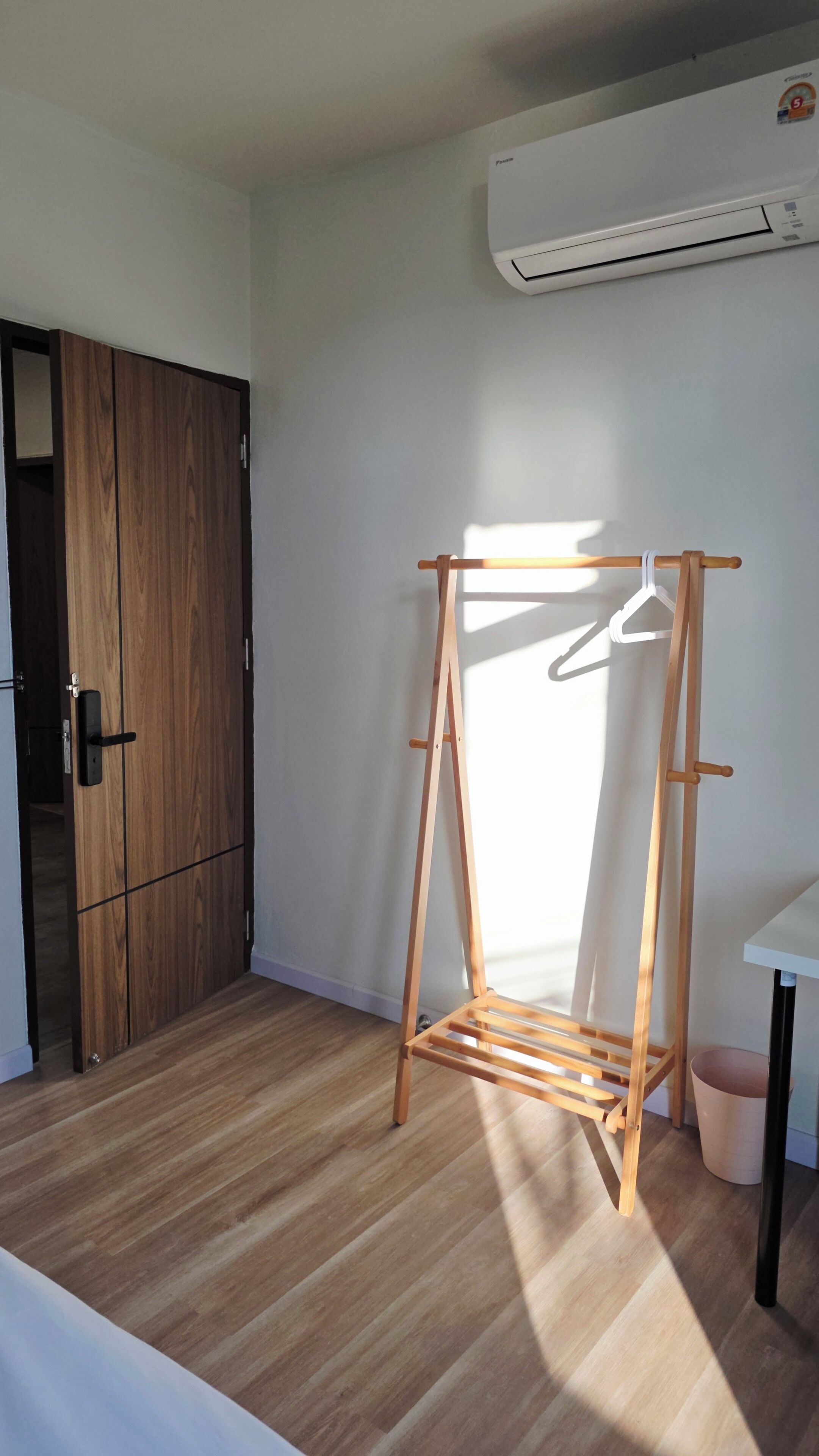 Een kamer met een houten garderobekast, een houten wasrek en een airconditioningunit aan de muur.