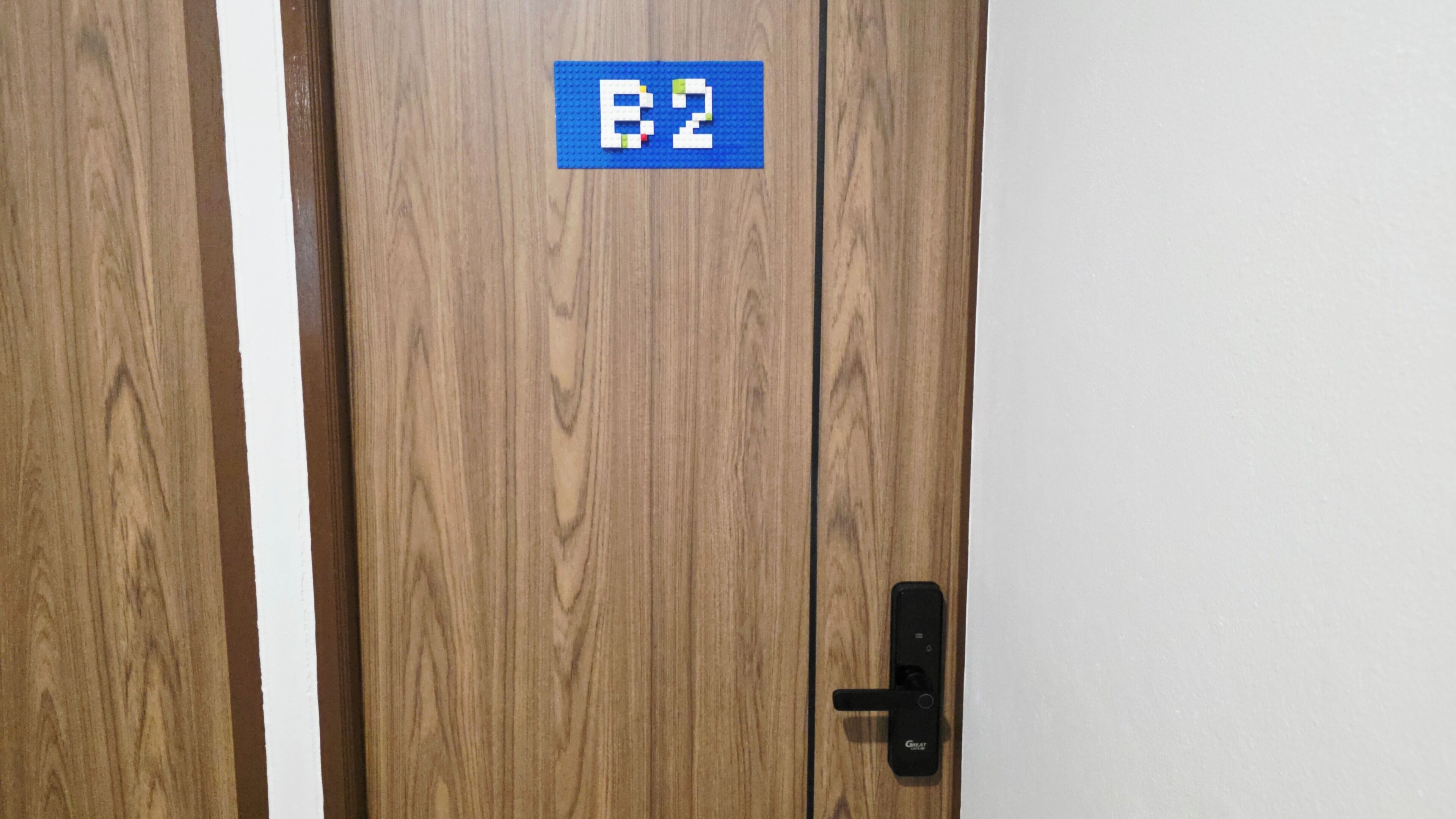Une porte en bois avec une plaque bleue portant l’inscription « B2 » et une serrure électronique noire.