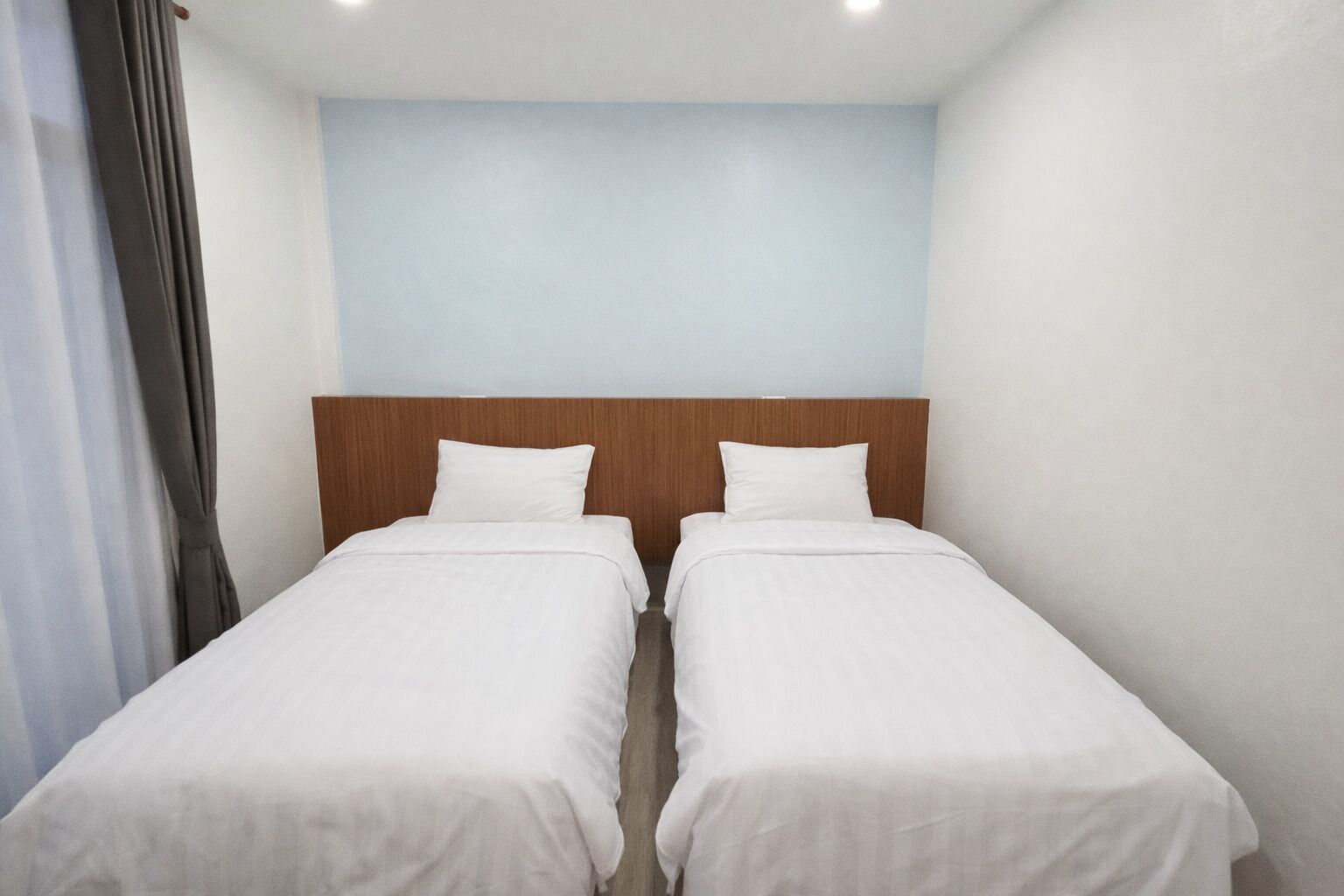 A twin room with two single beds, a wooden headboard, and a light blue wall.