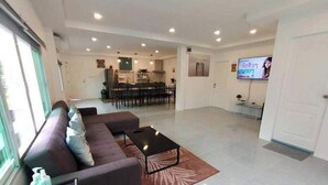 A modern living room with a sofa, coffee table, and a TV. - Baan Pink Pool Villa Pattaya (Bang Lamung)