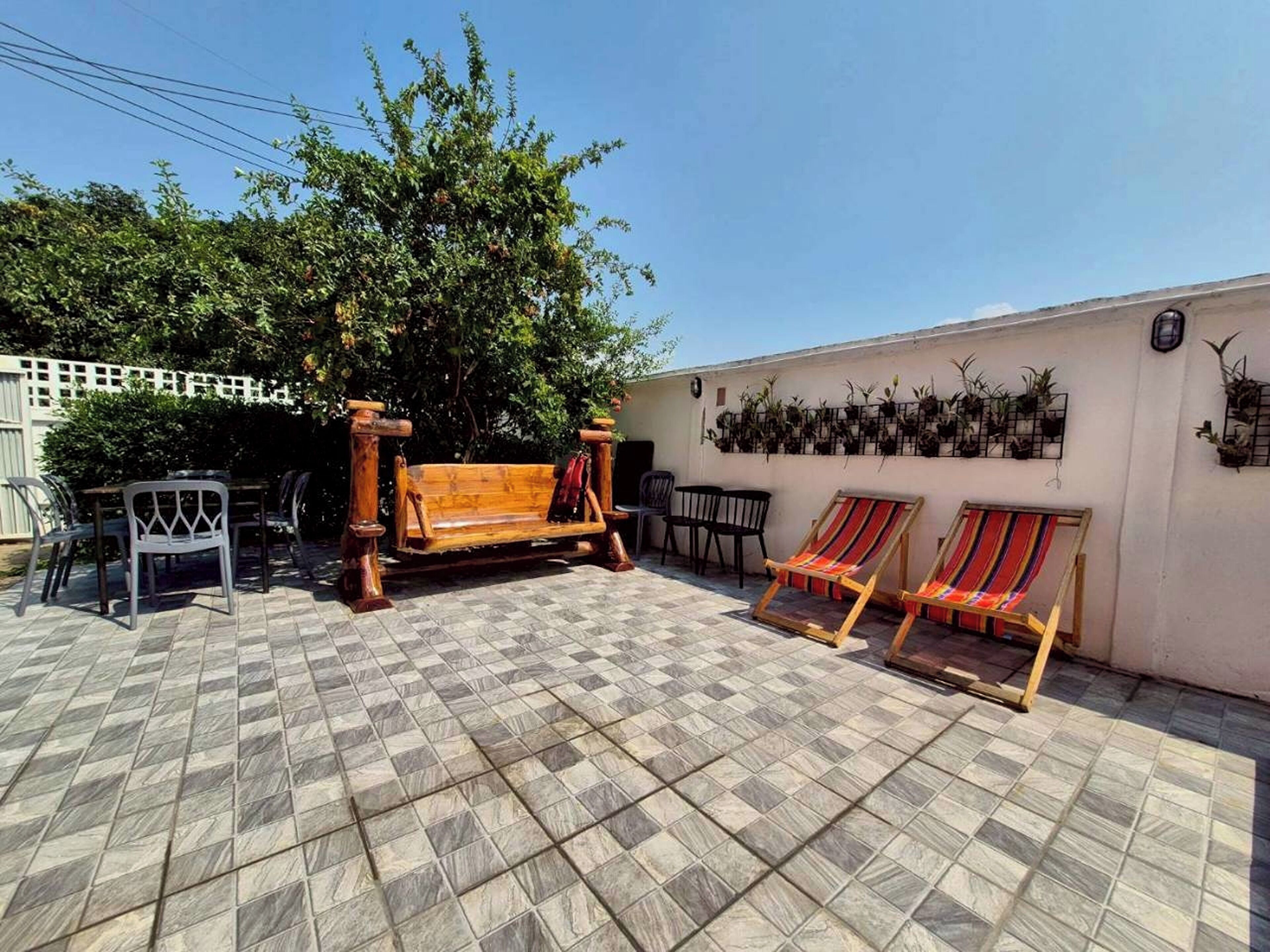 Eine Terrasse mit einer Holzbank, zwei gestreiften Liegestühlen und einem gefliesten Boden.