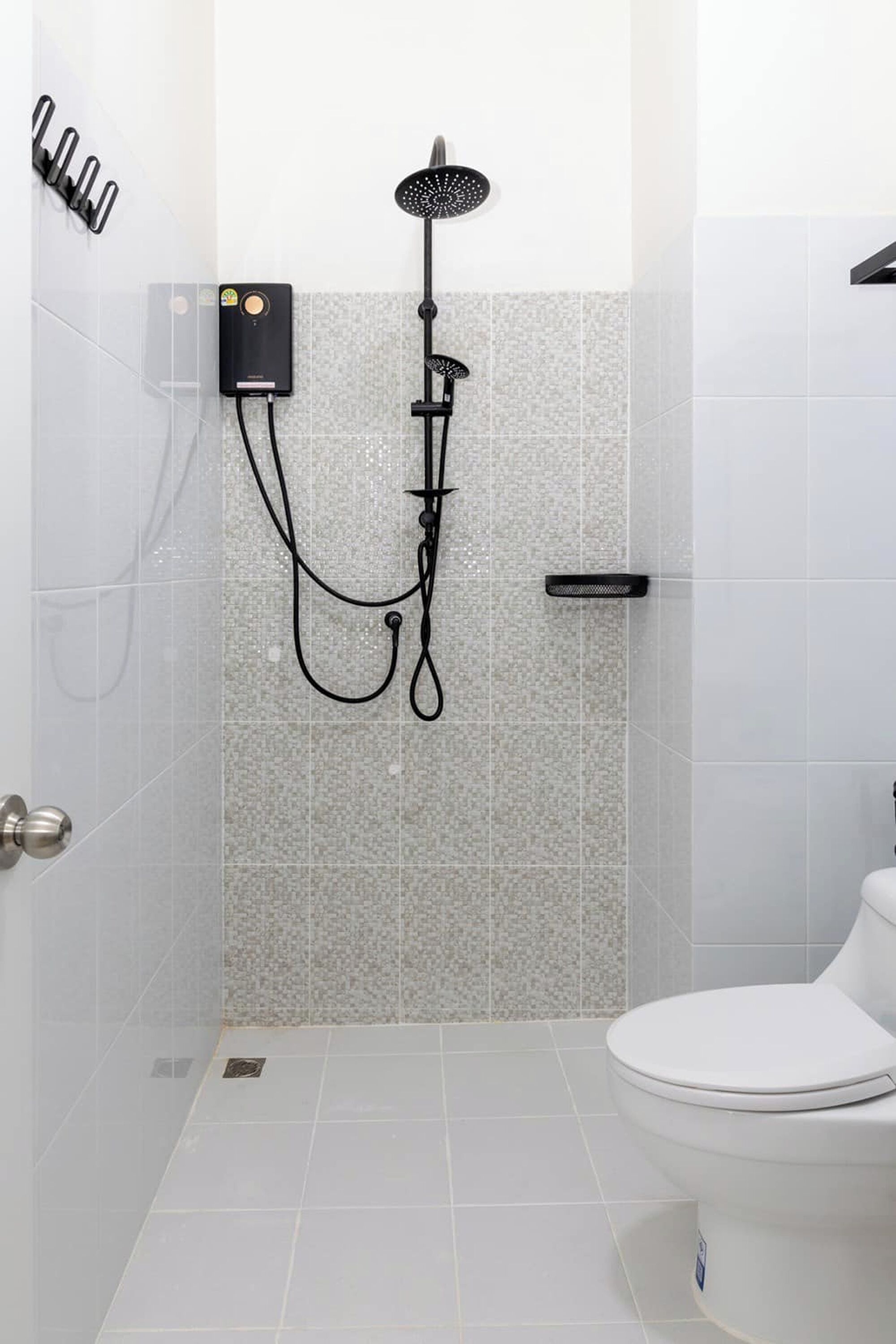 A bathroom with a shower, toilet, and a wall-mounted control panel.