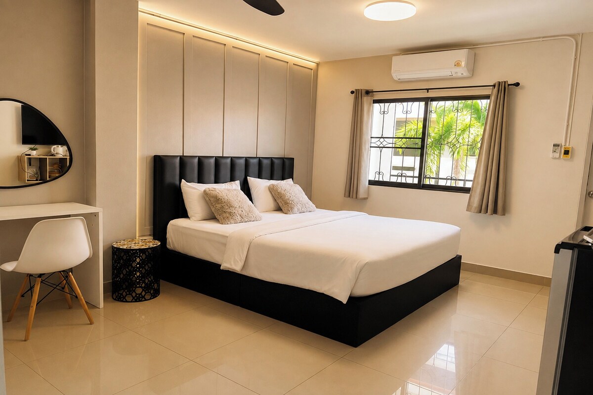 A modern bedroom with a large bed, a desk, and a window with curtains.
