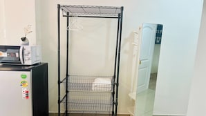 A metal rack with shelves, a microwave, a refrigerator, and a door with a mirror. - Dad N Mom'S House By Thongnak Apartment (Pattaya)