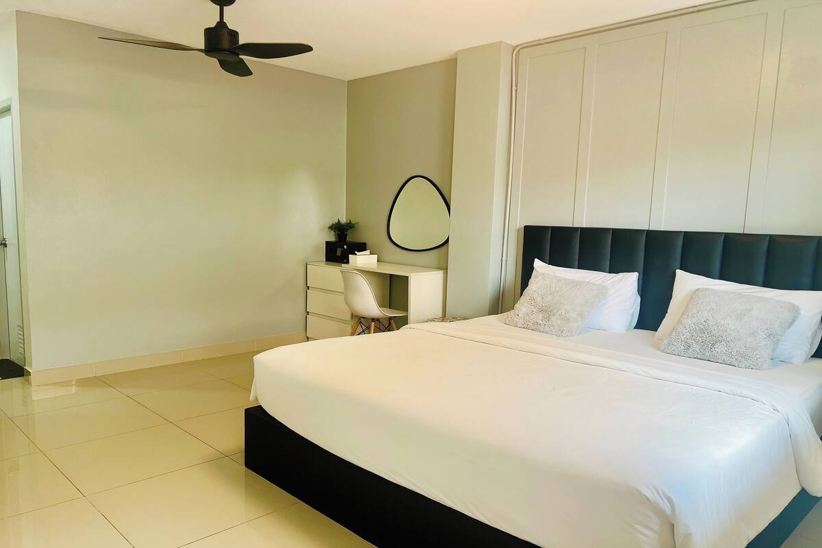 Un dormitorio con cama, escritorio, silla, ventilador de techo y espejo adosado a la pared.
