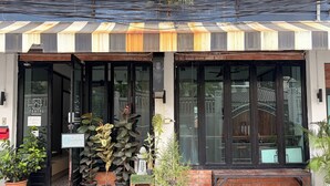 A hotel entrance with a sign indicating open hours, potted plants, and a tiled entrance area. - Teatel Ratchada (Bangkok)