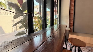 A wooden bench and a stool near a window with a view of buildings and plants outside. - Teatel Ratchada (Bangkok)
