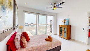 Une chambre à coucher avec un lit, un ventilateur de plafond, une armoire en bois et une vue sur l’extérieur.