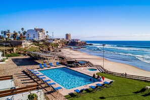 A pool area with blue lounge chairs, a small pool, and a beach view. - Dog-friendly home 3 rows to beach with rooftop deck, pool, hot tub, & kitchen (Rosarito)