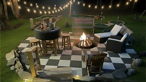 Un patio con fogón, mobiliario exterior e iluminación con luces colgantes.