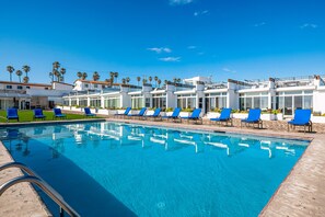A swimming pool with blue chairs and palm trees in the background. - Dog-friendly ocean-view retreat with pool access plus rooftop deck, AC (Rosarito)