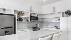 Eine moderne Küche mit weißen Schränken, einem Edelstahlkühlschrank, einer eingebauten Mikrowelle und einem Gasherd.