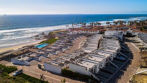Un hotel sulla costa con diversi edifici, una piscina e vista sulla spiaggia.