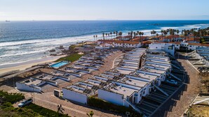 Un hotel frente al mar con varias construcciones, una piscina y vistas al océano.