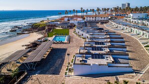 A coastal hotel with multiple rooftop terraces, a swimming pool, and a beach area. - Dog-friendly villa with heated pool, hot tub, streaming, partial ocean views (Rosarito)