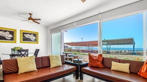 Ein modernes Wohnzimmer mit einem braunen Ledersofa, einem Glastisch und Blick auf den Strand.