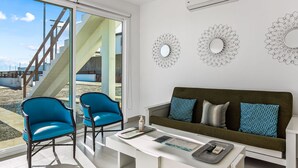 Un salon moderne avec un canapé, deux fauteuils bleus, une table basse et des miroirs décoratifs fixés au mur.