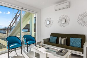 A modern living room with a sofa, two blue chairs, a coffee table, and decorative wall mirrors. - Dog-friendly beachfront villa with pool & hot tub access plus rooftop deck (Rosarito)