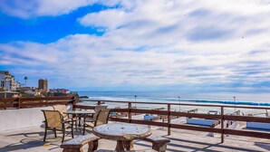 Un espace extérieur aménagé avec des sièges et offrant une vue sur la plage et l’océan.