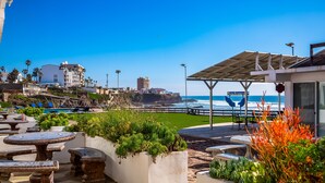 A coastal patio with outdoor seating, a view of the ocean, and a rocky outcrop in the background. - Peaceful dog-friendly villa with outdoor pool, rooftop patio, beach views, & AC (Rosarito)
