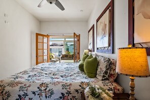 Un dormitorio con cama, lámpara y vistas a un balcón exterior.