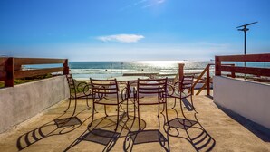 Une terrasse dotée de chaises et de tables en métal, offrant une vue sur l’océan.