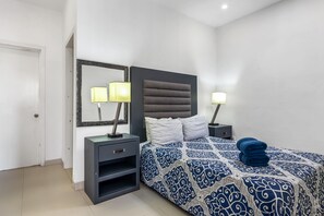 Une chambre à coucher avec un lit, des tables de chevet, un miroir et une porte.