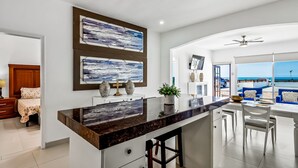 A modern kitchen with a marble countertop, two large abstract paintings, and a view of the beach through large windows. - Dog-friendly villa with heated outdoor pool, hot tub, streaming, private patio (Rosarito)