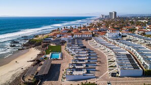 A coastal hotel with multiple buildings, a beach, and a pier.