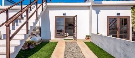 Un bâtiment moderne doté d’un escalier menant à un balcon situé au deuxième étage, d’un chemin de gravier et d’une pelouse bien entretenue.