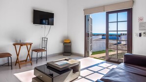 A modern living room with a flat-screen TV, a sofa, a coffee table, and a dining area with chairs.
