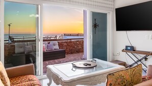 A living room with a glass table, a sofa, and a TV mounted on the wall. - Dog-friendly ocean-view villa with patio, outdoor pool, streaming, partial AC (Rosarito)