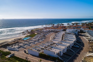 Un hôtel situé sur la côte, composé de plusieurs bâtiments, doté d’une piscine et offrant une vue sur la plage.