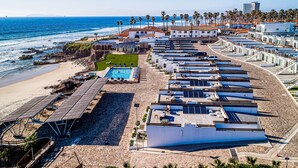 Ein Küstenhotel mit mehreren Dachpools, einem Strandbereich und Blick auf den Ozean.