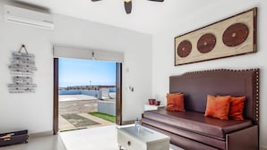 Una sala de estar moderna con un sofá marrón, una mesa de centro blanca y un amplio ventanal con vistas a una piscina y zona exterior.