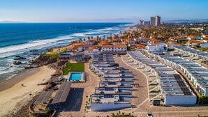 Una zona costera con una hilera de edificios blancos, una playa y un muelle que se extiende hacia el océano.