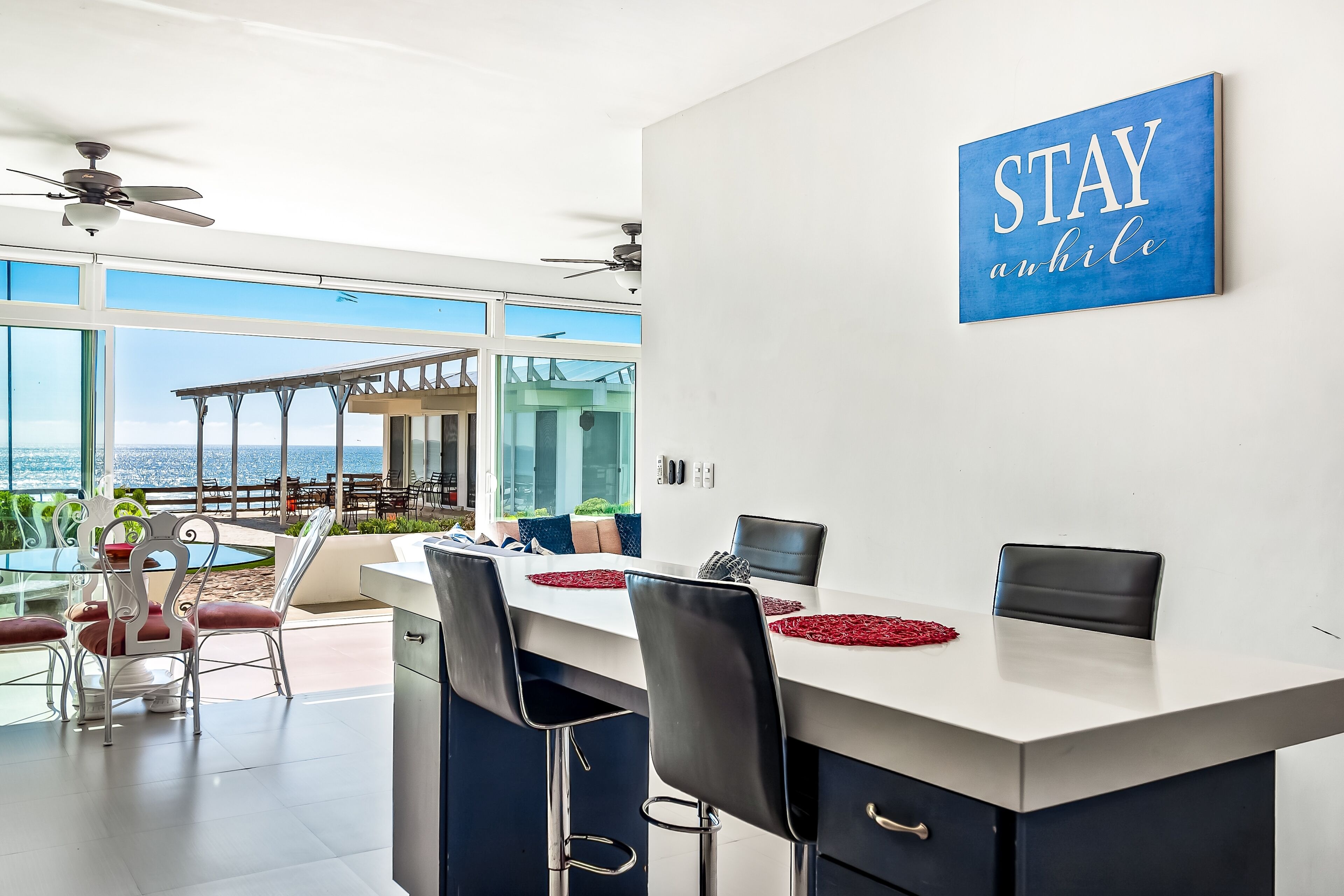 A modern kitchen with a large island, white cabinets, and a view of the outdoors.